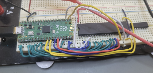 a breadboard with a raspberry pi pico 2, and an NEC D765AC floppy disk controller chip, connected with colored hook-up wires.