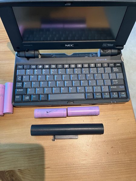 a nec mobilepro handheld computer with its battery pack removed. the pack has room for two 18650 lithium cells, shown in pink above the battery case. 